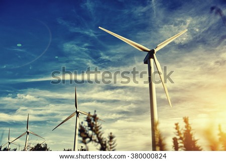 Wind turbines against beautiful cloudy sky, electric generators in countryside with sun says on background, renewable energy sources, windmills outside the city