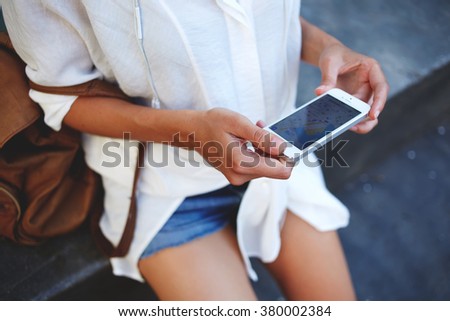 Cropped shot view of woman tourist holding mobile smart phone with navigation application and planned route on the screen, female looking at something on a cell telephone while touring a foreign city