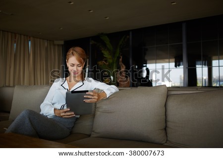 Gorgeous woman dressed in elegant clothes watching video on digital tablet while relaxing in cozy restaurant, young female entrepreneur reading world news in internet via touch pad during work break
