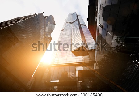 View from below of a tall skyscrapers in business district in sunny evening. Exterior of a modern office buildings in metropolitan city against beautiful sunset