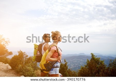Young beautiful woman and man travelers are enjoying hike and beauty nature view during rest in the fresh air, two wanderers are taking break between walking in mountains during their summer adventure