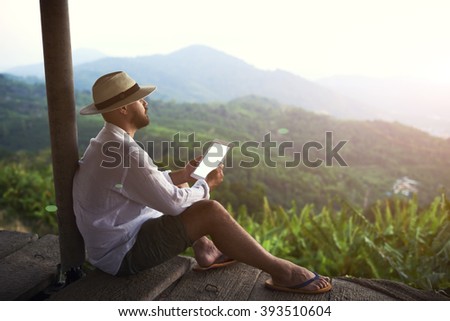 Man traveler is holding digital tablet with copy space on the screen for your advertising text message, while is admiring amazing Latin American landscape during the long-awaited summer vacation