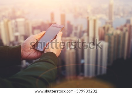 Closeup of man`s hands is holding smart phone with copy space screen for your advertising text message. Closely of male manager is watching wold news online via cell telephone during work break
