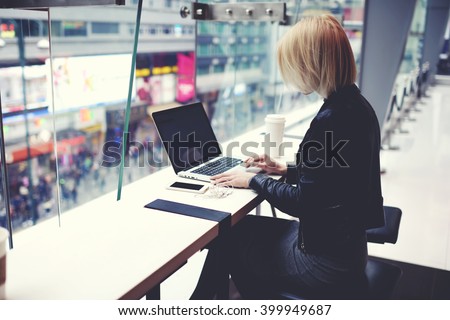 Stylish hipster girl is using for remote freelance job portable net-book during her vacation in China.Female student is searching information in internet via laptop computer during rest after shopping