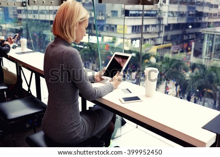 Businesswoman is reading world news on touch pad with copy space screen for your advertising text message or content. Young female is watching video on digital tablet during rest in modern coffee shop
