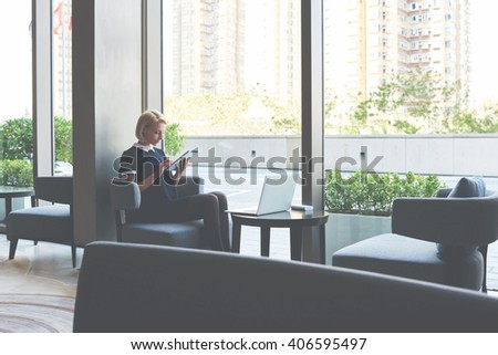 Female student is checking e-mail on digital tablet, while is waiting file download on laptop computer. Businesswoman is ordering on-line car via touch pad, while is sitting with net-book in cafe