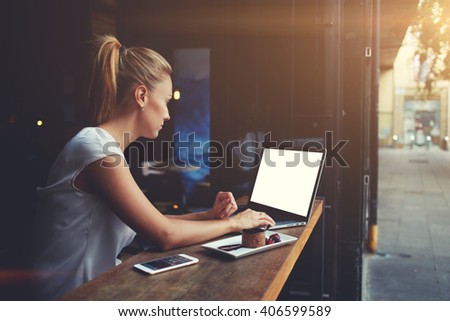 Young female student working on net-book with blank copy space screen for your text message or promotional content, cute woman successful freelancer using laptop computer while sitting in coffee shop