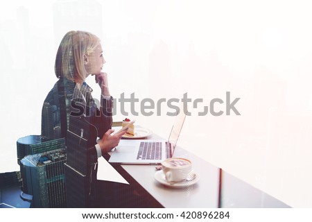 Double exposure with hipster girl with mobile phone thoughtful look away, while is sitting  at the table of modern coffee shop with open laptop computer. Woman freelancer using cell phone and net-book