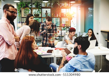 Group of diverse college students sitting together and studying on campus. Friends or business colleagues talking and discussing work ideas in office during informal meeting. Concept of team startup