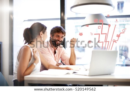 Couple of young designers working at modern office, two coworkers discussing startup project over laptop,team of businesspeople smiling and looking together at computer, Infographics multimedia effect