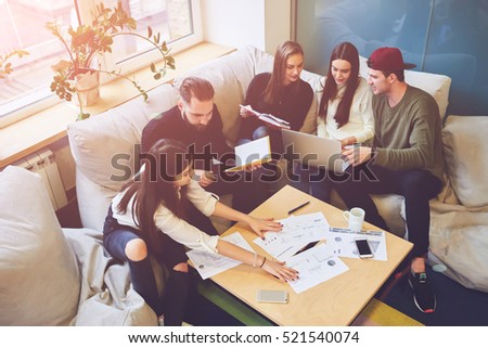 Young team of freelancers searching information making business tasks consulting with expert. Students preparing presentation using technology modern laptop wireless internet connection in coworking