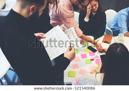 Teacher in business school checking coursework of student reading information making accounts.Young architects share with skilled coworkers ideas written in notebook  choosing successful strategy