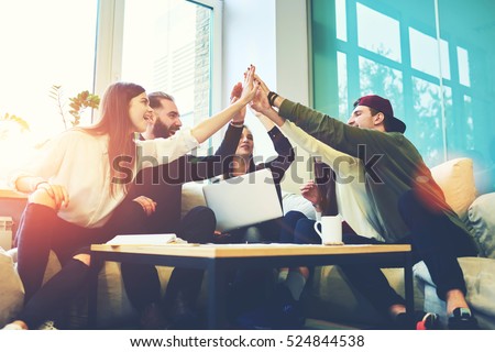 Female and male classmates celebrating pathing math examination, feeling exciting and cheerful , giving high five during informal meeting in friendly atmosphere with modern laptop in coworking space