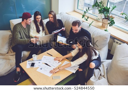 Female and male classmates doing homework for business course, accounting data, making graphic illustrations during informal meeting in friendly atmosphere with modern laptop in coworking space