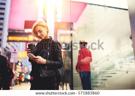 Young female travel blogger enjoying coffee in morning while making city tour using application with online maps on modern smartphone connected to fast 4G internet in roaming fascinating by Hong Kong