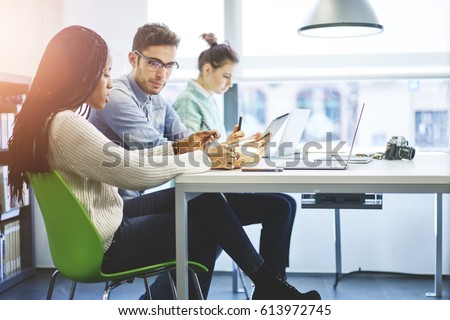 Skilled male and female marketing experts collaborating creating advertising campaign for web store using modern technologies and wireless connection in coworking office sharing ideas for project