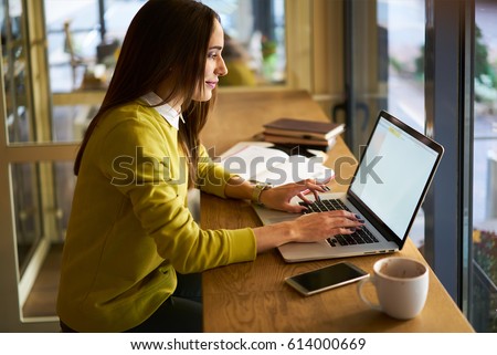 Smiling attractive woman in good mood earning money from internet advertising working on freelance during leisure in coffee shop,female owner of marketing company checking email box via laptop