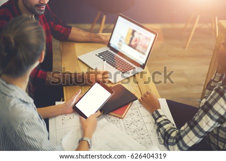 Professional male and female journalist making planning for article publication using laptop computer watching webinar, skilled designers sharing creative ideas for web project cooperating in office