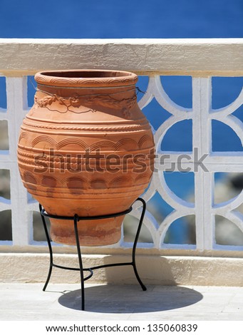 Large clay pot is usual decoration on the terrace of Greek guest house. The contrast between white fence and the blue color of Mediterranean sea forms a formidable background. Island Kalymnos, Greece.