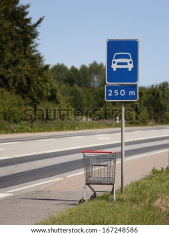 abandoned shopping cart at the limited-access road sign. concepts: consumption crisis, absurd, wtf, making choices, leave behind  ...