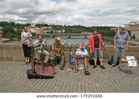 PRAGUE, CZECH REPUBLIC - AUGUST 3, 2008: Street musician play on the Charles Bridge. It is a bridge that crosses the Vltava river, connecting old town with the castle hill.