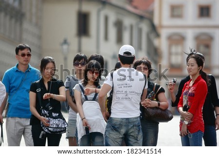 PRAGUE, CZECH REPUBLIC - AUGUST 3, 2008: Photo showing a group of tourists with their guide. Obviously they are discussing the schedule. Focus is on guide\'s funny t-shirt of Spanish origin.