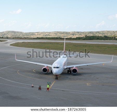KOS, GREECE - JUNE 23, 2010: Large commercial plane owned by company Air Berlin landed on the Greek island of Kos and is nearly stopped on apron. In the background typical landscape can be observed.