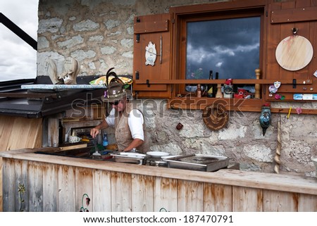 CORTINA, ITALY - JUNE 27, 2012: Photo showing an outside bar with administrator  partially dressed in local outfit at Rifugio Nuvolau situated on the top of mounte Nuvolau (2574 m).