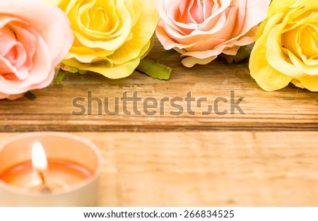 Colorful roses and candle among roses on wood background useful as esoteric backgrounds