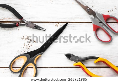 Pincers and scissors tools on wood background