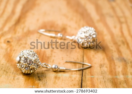 Earrings in beads shape, made with silver and crystal glass isolated on wood background