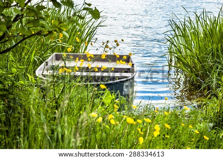 Moored rowing boat for fishing on the lake at the shore among the reeds. Outdoor wedding theme. Theme of vacation, holiday, leisure and relaks.