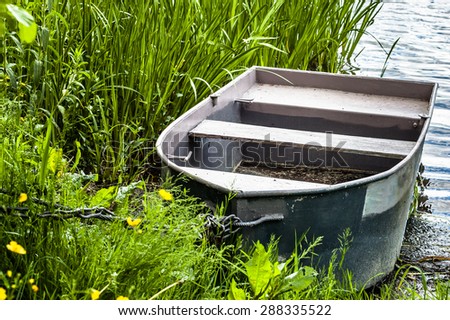 Moored rowing boat for fishing on the lake at the shore among the reeds. Outdoor wedding theme. Theme of vacation, holiday, leisure and relax.