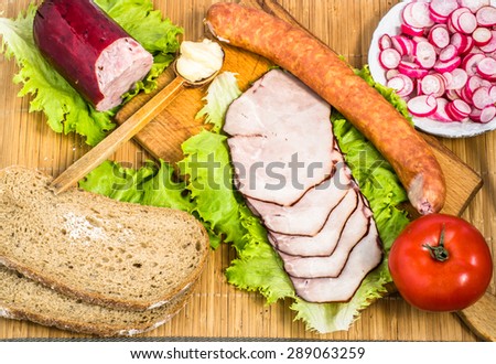 Sausages with vegetables and bread for breakfast or dinner on cutting board and bamboo mat.