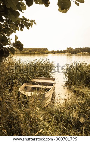 Vintage photo of boat for fishing on the lake at the shore. Summer holiday and vacation theme, leisure and relax. Nature background or landscape, vintage effect.