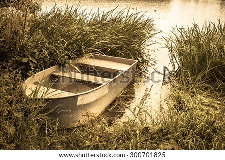 Vintage photo of boat for fishing on the lake at the shore. Summer holiday and vacation, leisure and relax. Nature background or landscape, vintage effect.
