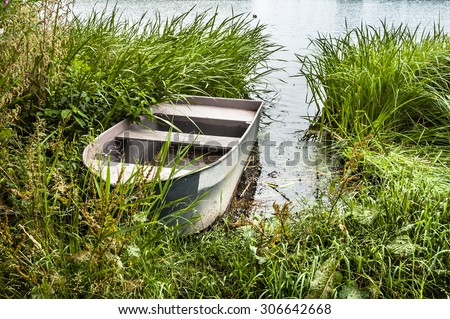 Photo of old boat for fishing on the lake at the shore among the reeds. Outdoor wedding theme. Theme of vacation, holiday, leisure and relax.