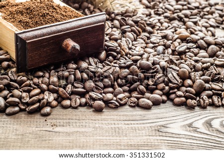 Black coffee beans and coffee powder on wooden table with copy space, selective focus.