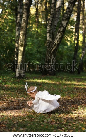 Little girl sitting in forest with angel wings in white dress. Halloween