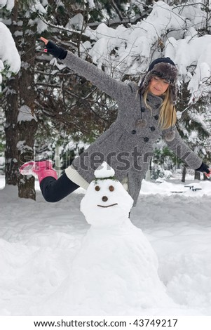 Angry girl in winter clothing is about to kick snowman
