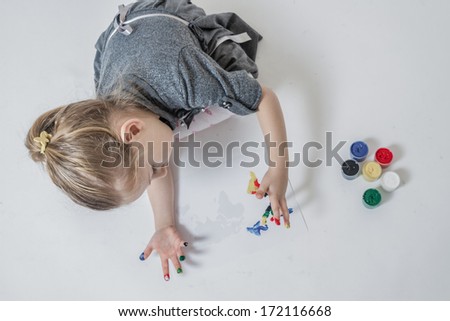 Little girl playing with colors by painting finger paints