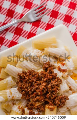 Pasta with meat and tomato sauce on red and white checked napkin