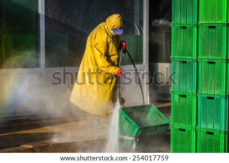 Worker cleaning green boxes in yellow safety protective equipment