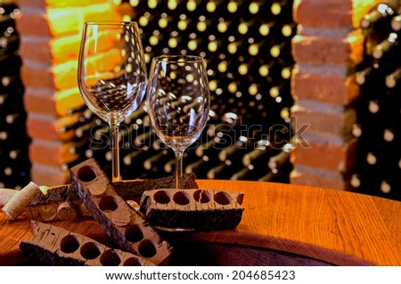 wineglasses with cork stoppers and cork bark standing in front of brick boxes of bottles of wine