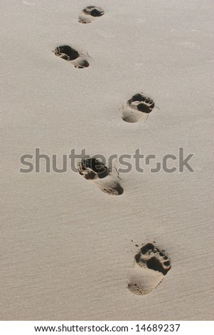bare feet footprints in wet sand walking away.
