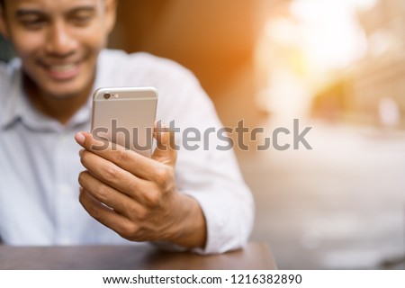 Close up asian man using smart phone mobile device for play or shopping online or check time and date , teenager with technology concept