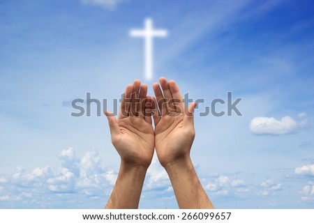 Two hands pray with cross blurred sky background , soft focused.