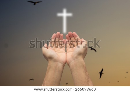 Two hands pray with cross blurred twilight sky background , soft focused.