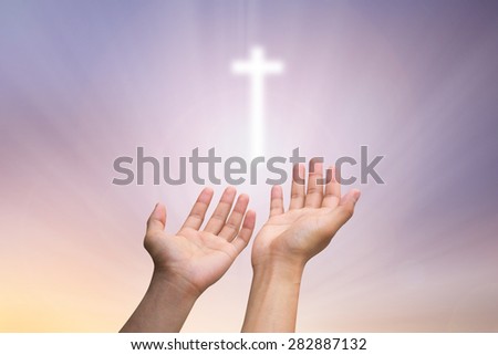 human's hands praying  cross  on blurred twilight sky background   , soft focused.