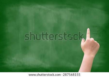 Hand pointing on empty green blackboard background.